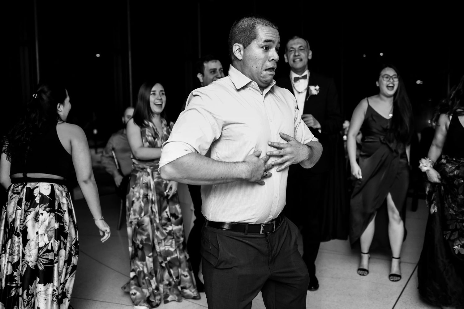Wedding guests dance at a lively reception in black and white photography.