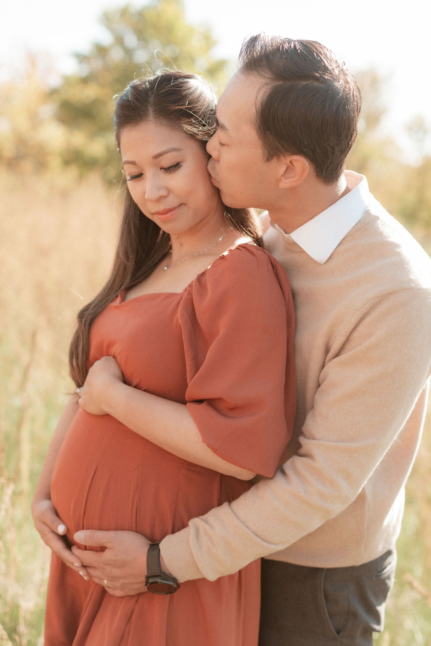Couple shares an intimate moment in a field while wearing coordinated autumn tones.