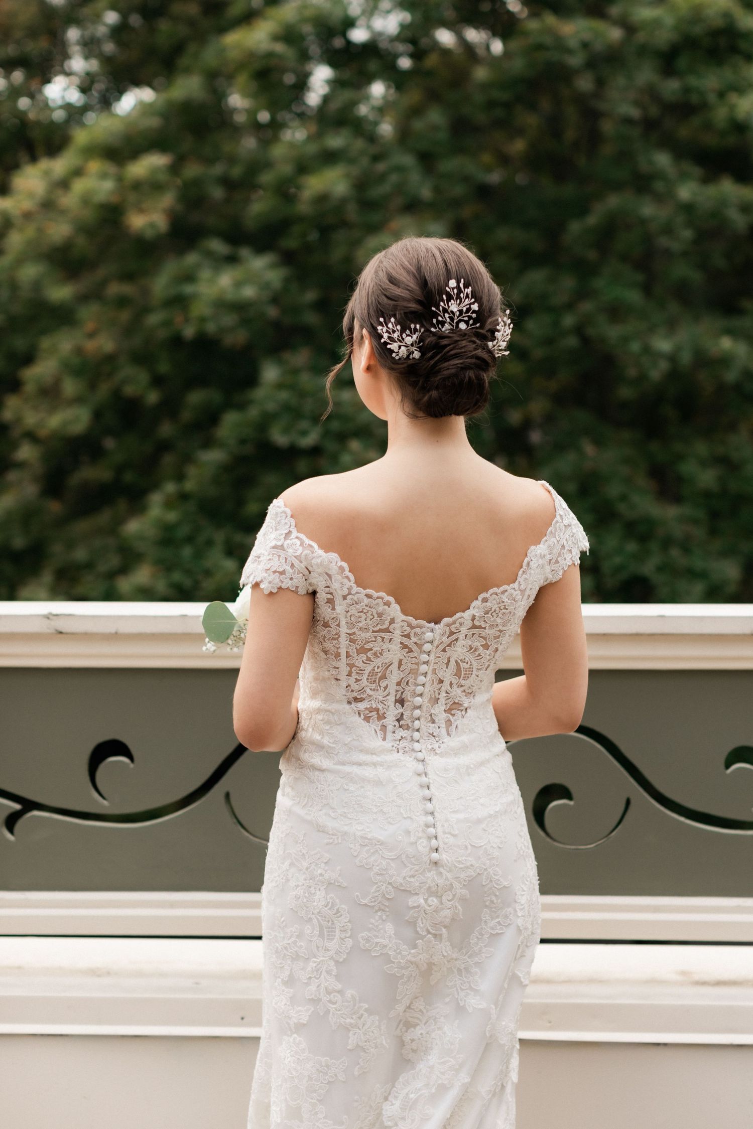 Back detail of lace wedding dress with crystal hair accessories on balcony.