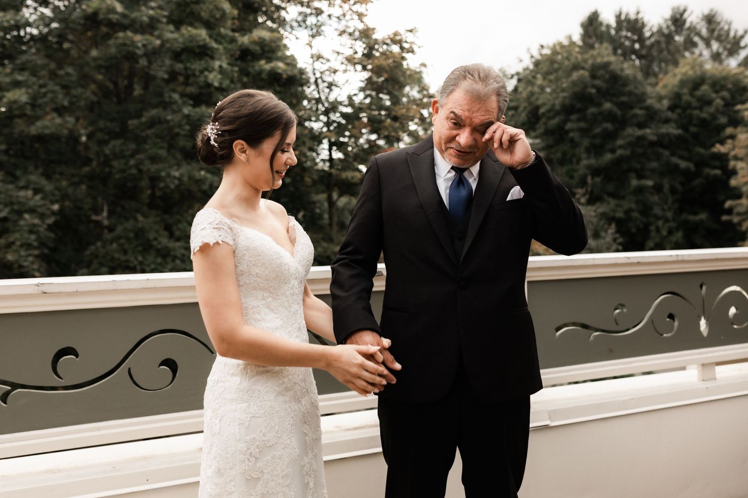 A tender moment shared during a wedding ceremony on an ornate white balcony.