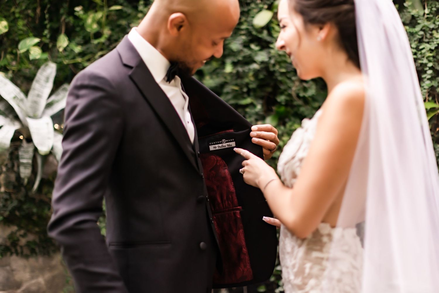 Couple examines wedding rings during an intimate garden ceremony moment.