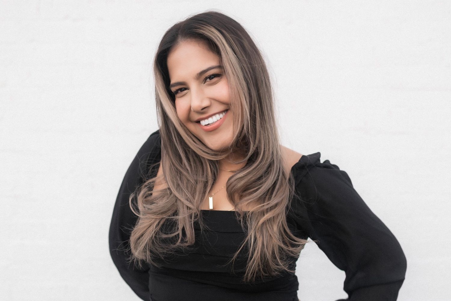 Portrait of woman in black top smiling against white background.