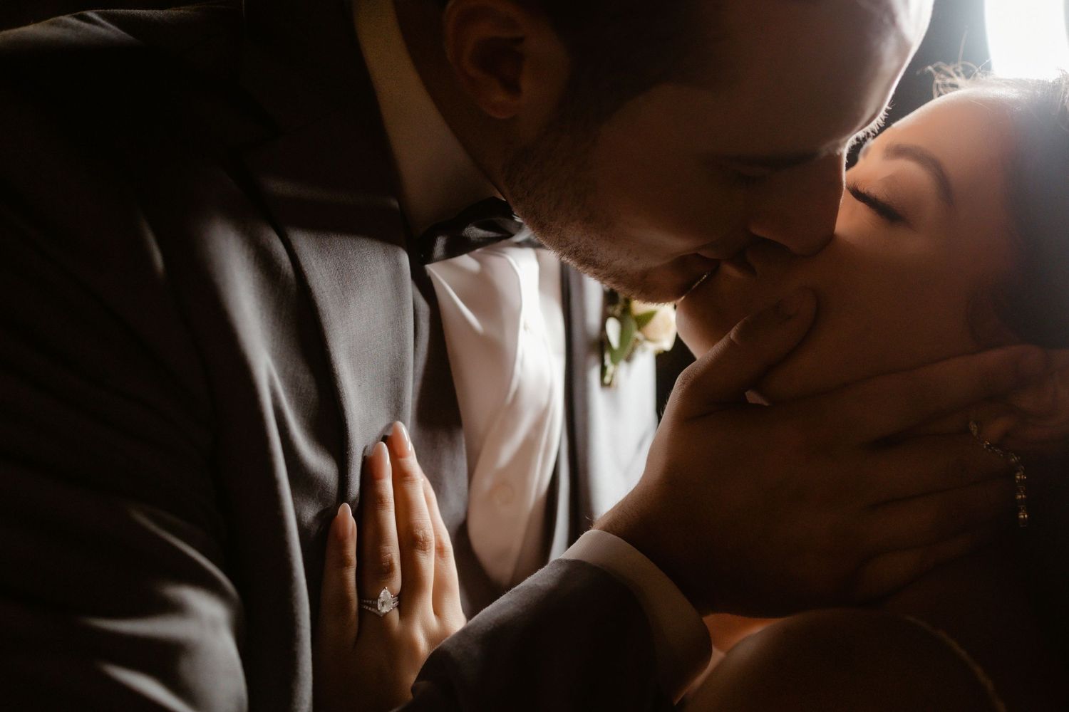 Intimate portrait of newlyweds in dramatic lighting sharing a tender moment.