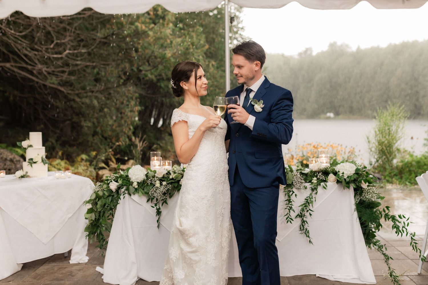 A newlywed couple shares an intimate moment by their flower-decorated reception table.