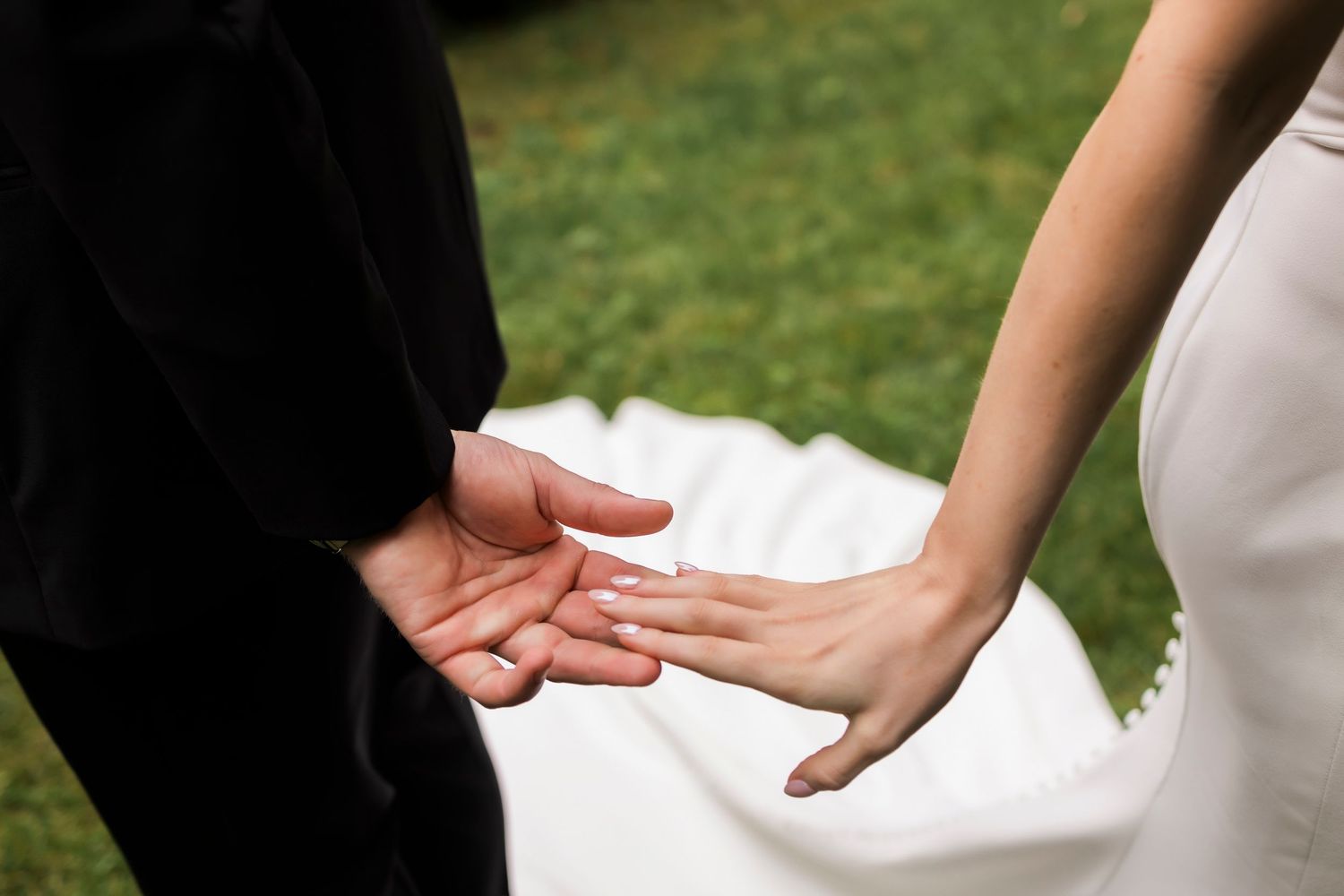 Close-up shot of hands during wedding ceremony in outdoor setting.