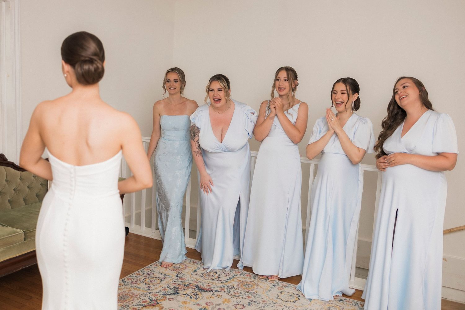 A group wearing coordinated light blue and white bridesmaid dresses stands together in a bridal party setting.