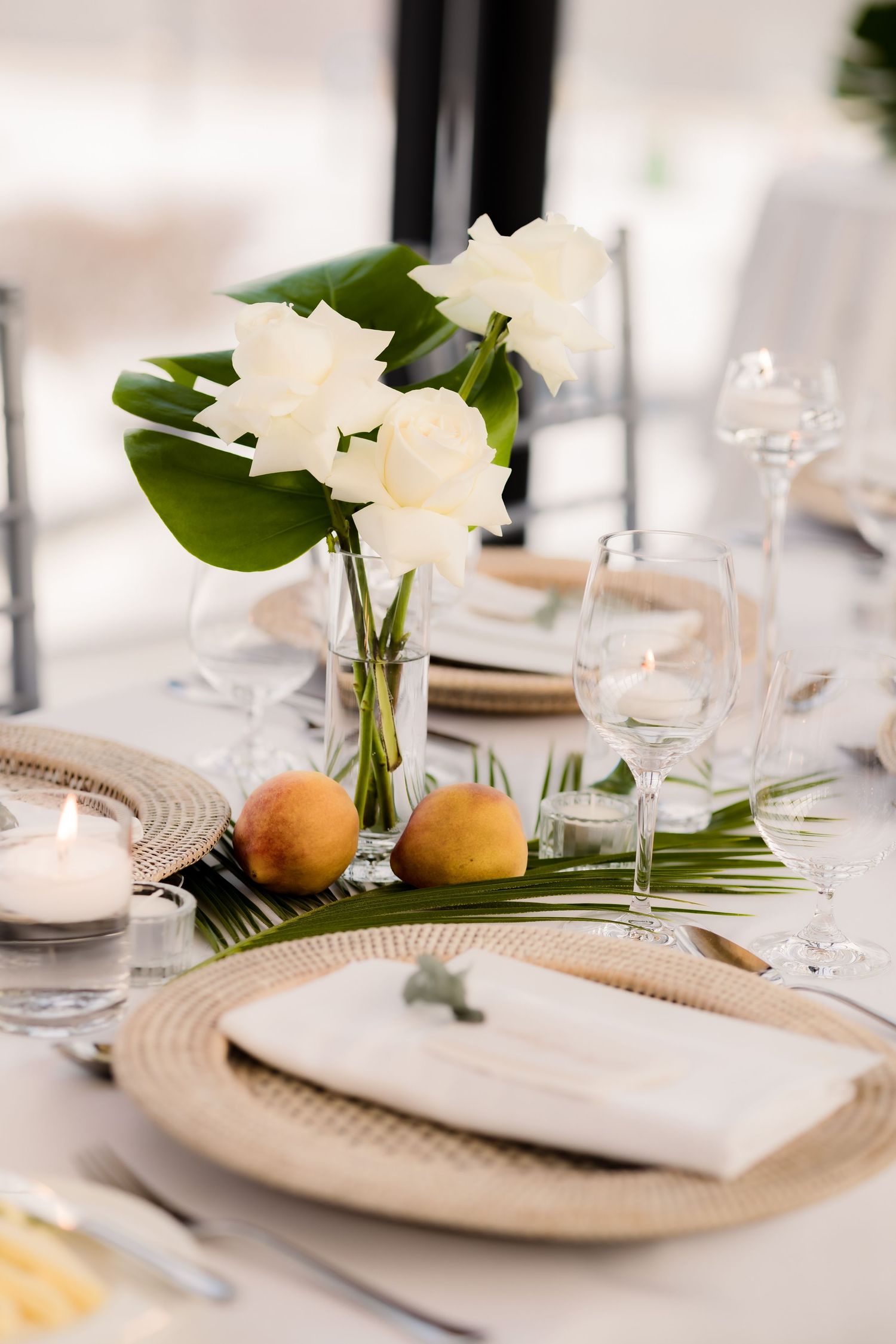 Tropical wedding table setting with palm fronds, white flowers and gold charger plates.