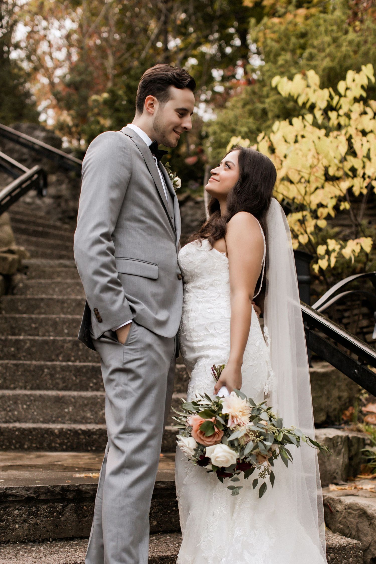 Romantic wedding couple shares intimate moment on stone steps in garden setting.