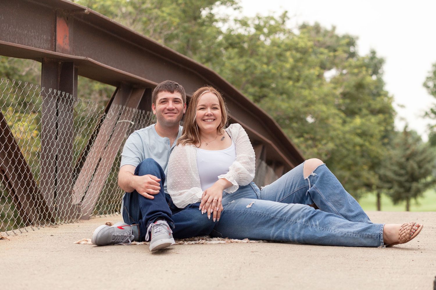 Couple relaxing together on a rustic bridge during outdoor photoshoot.