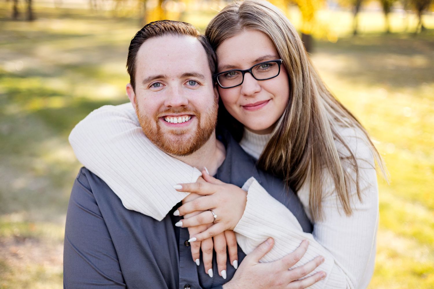 A sweet engagement photo showing off a ring during an autumn photoshoot.