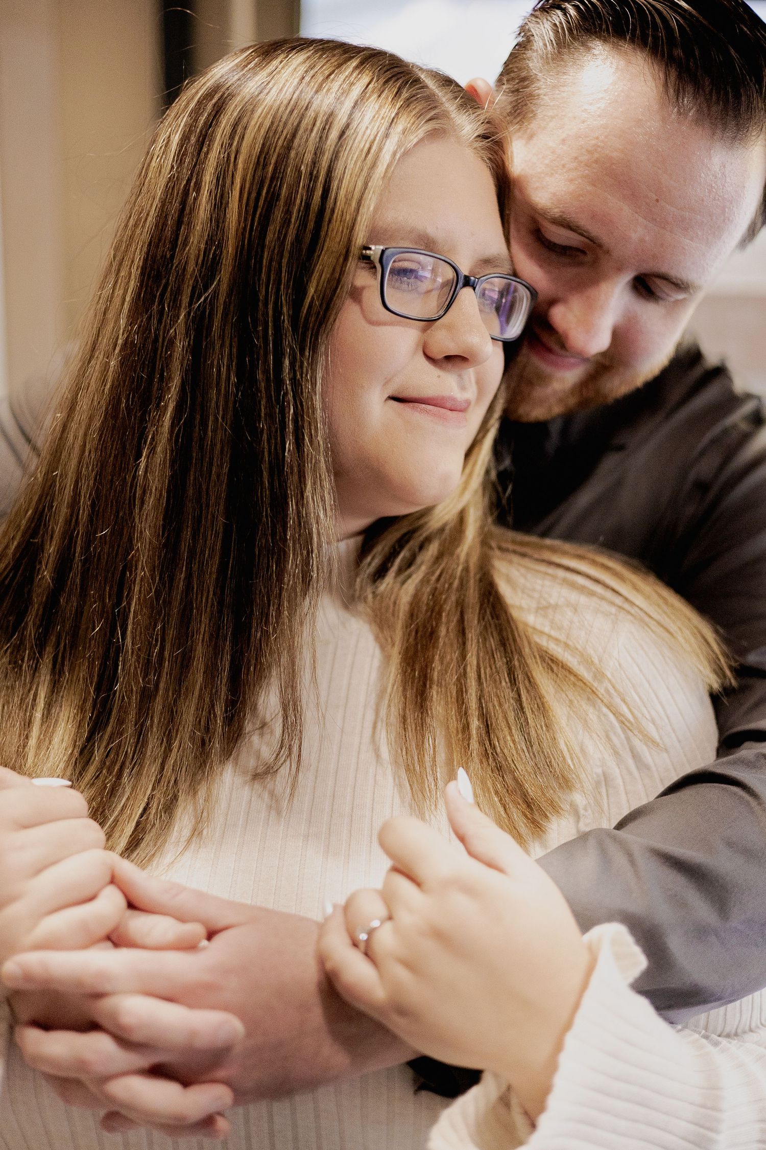 A tender indoor portrait of a couple embracing in warm light.
