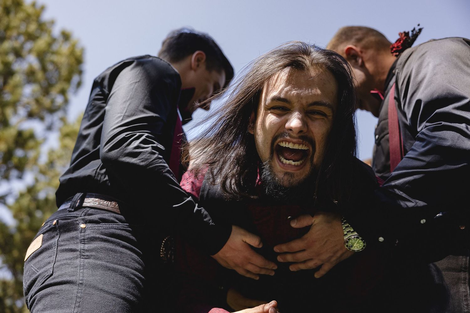 Joyful group moment captured outdoors with people laughing and hugging.
