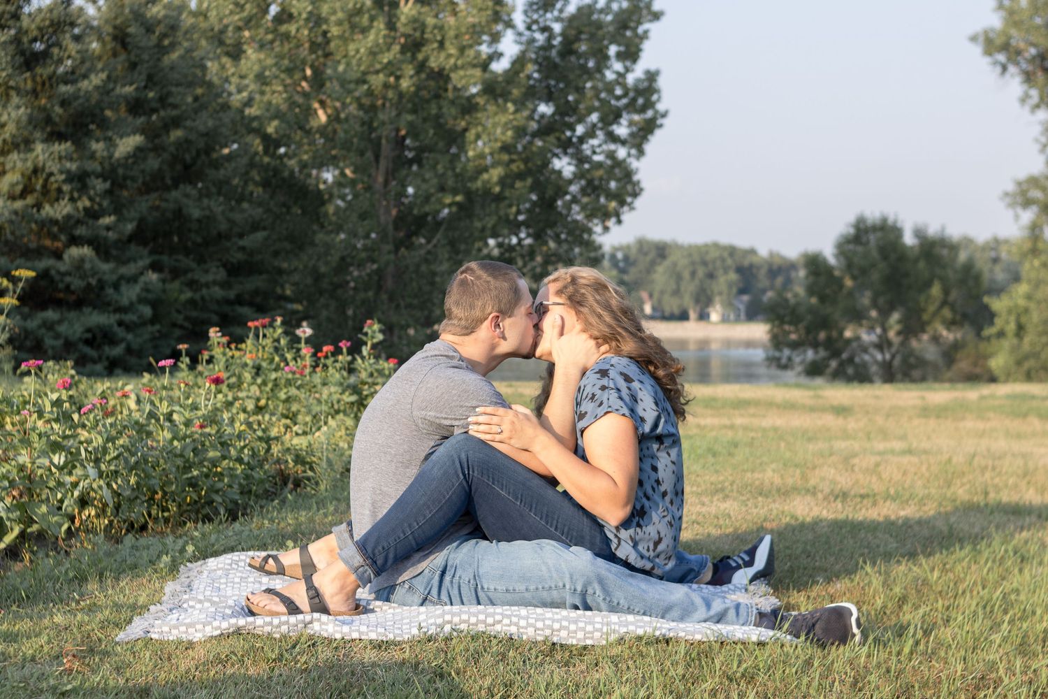 A couple shares an intimate moment on a blanket in a summer field.