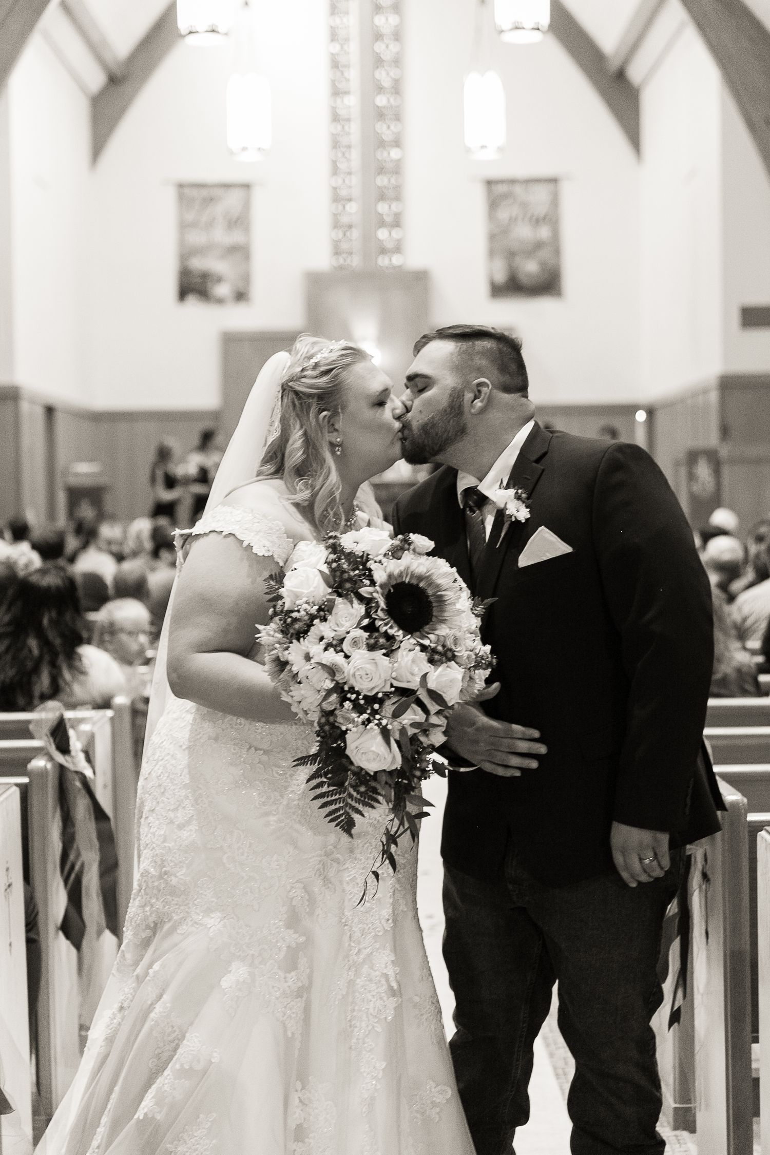A romantic wedding ceremony moment captured in black and white inside a traditional church setting.