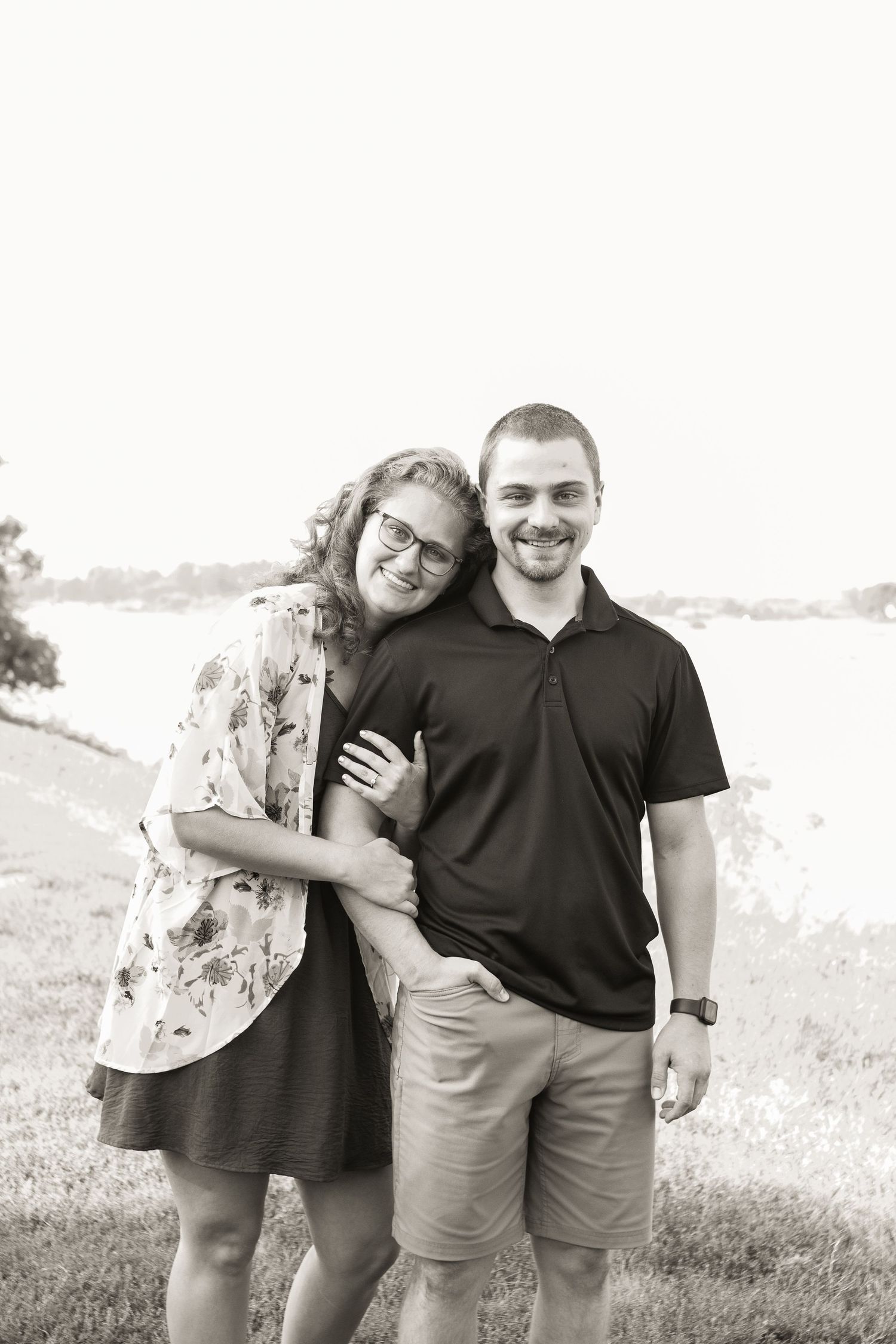 A couple shares a candid black and white moment outdoors.