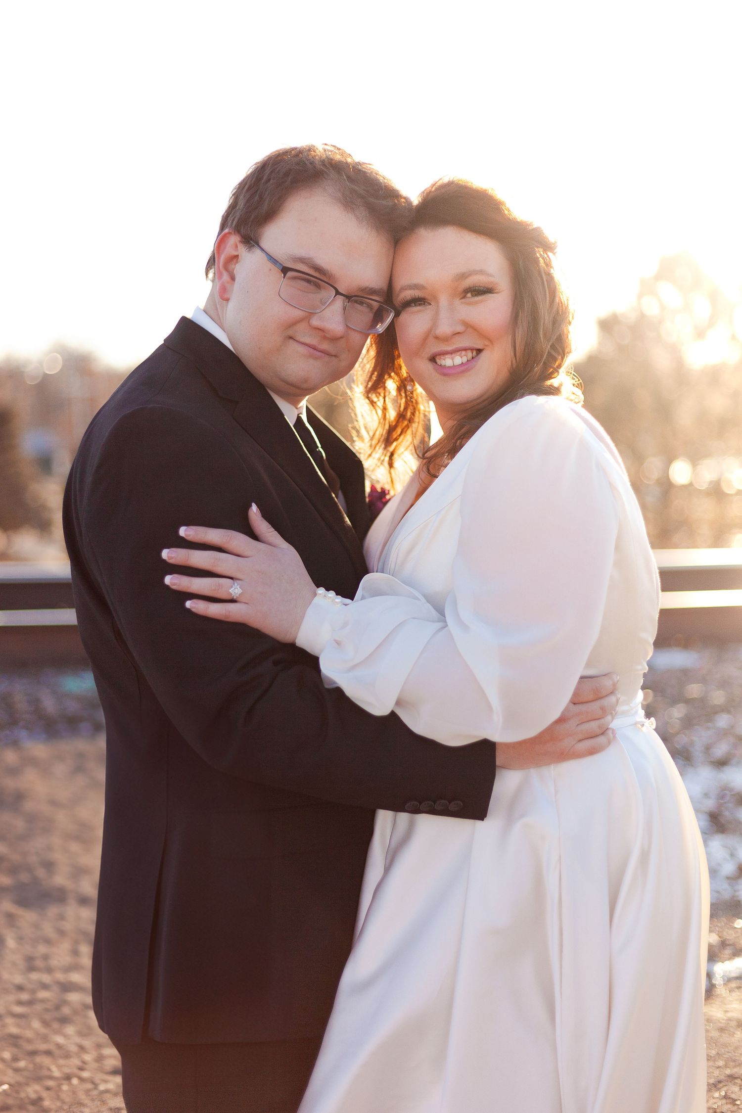 Sunlit winter wedding portrait of couple embracing outdoors.