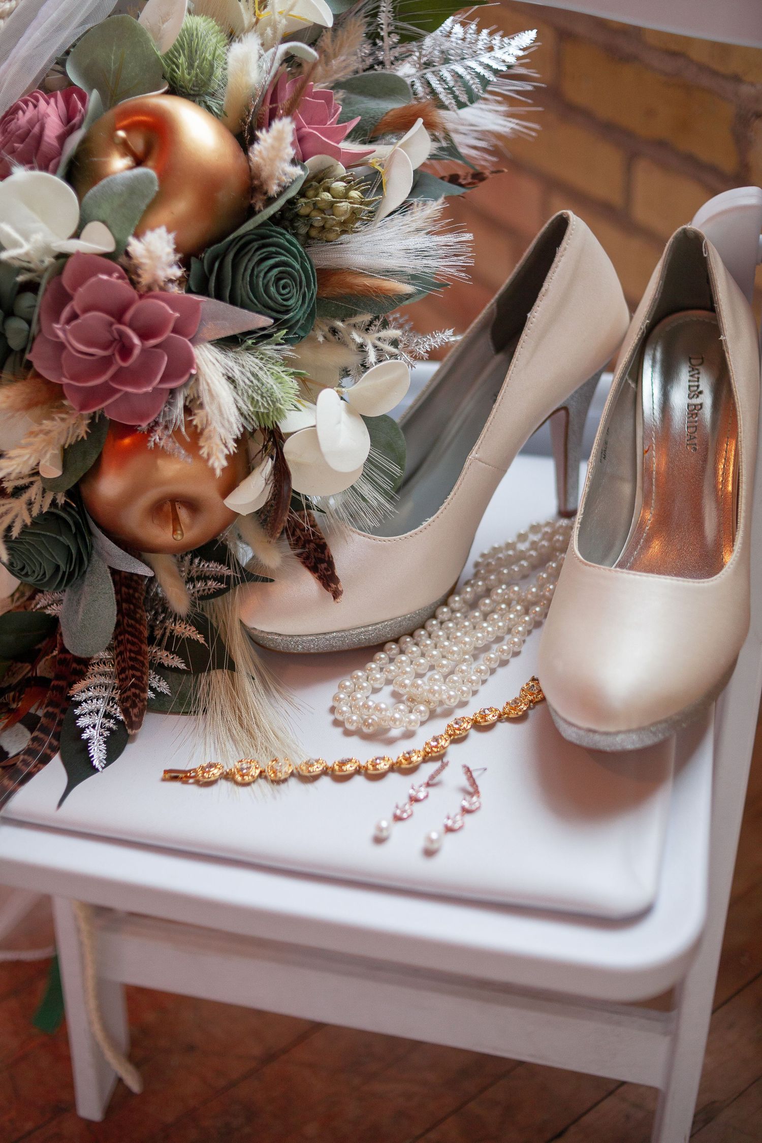 Bridal accessories featuring blush heels, pearls, and a lush autumnal bouquet with burgundy and peach flowers.