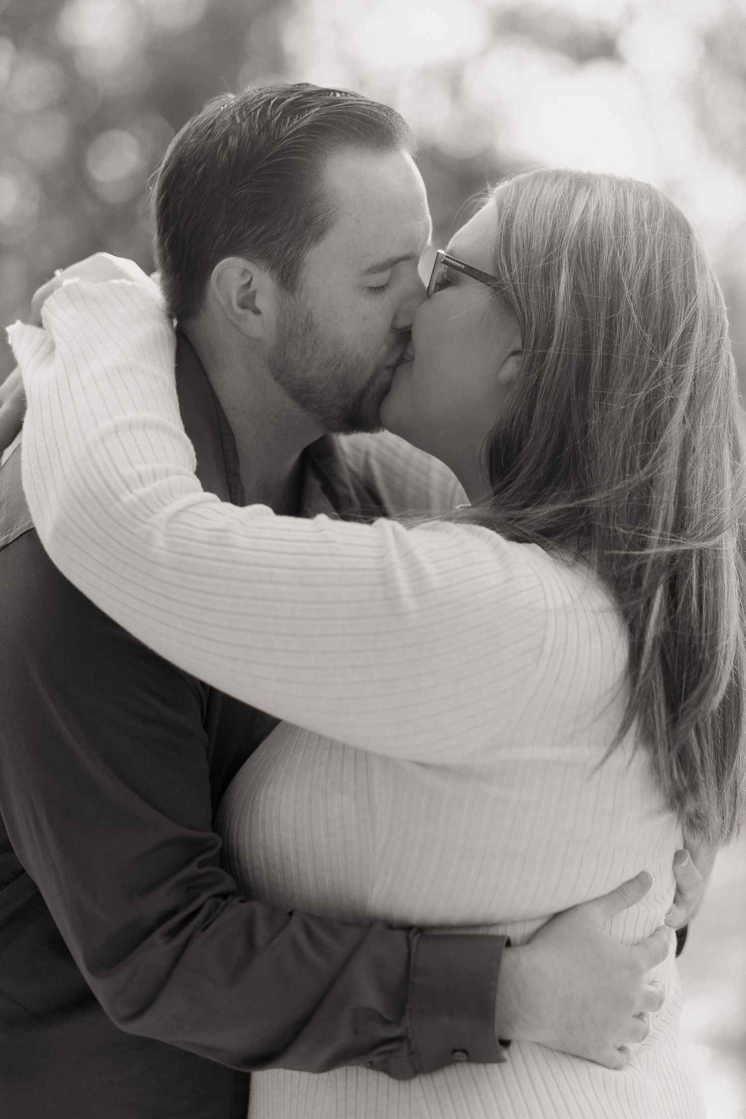 A black and white close-up of a couple sharing a romantic kiss.