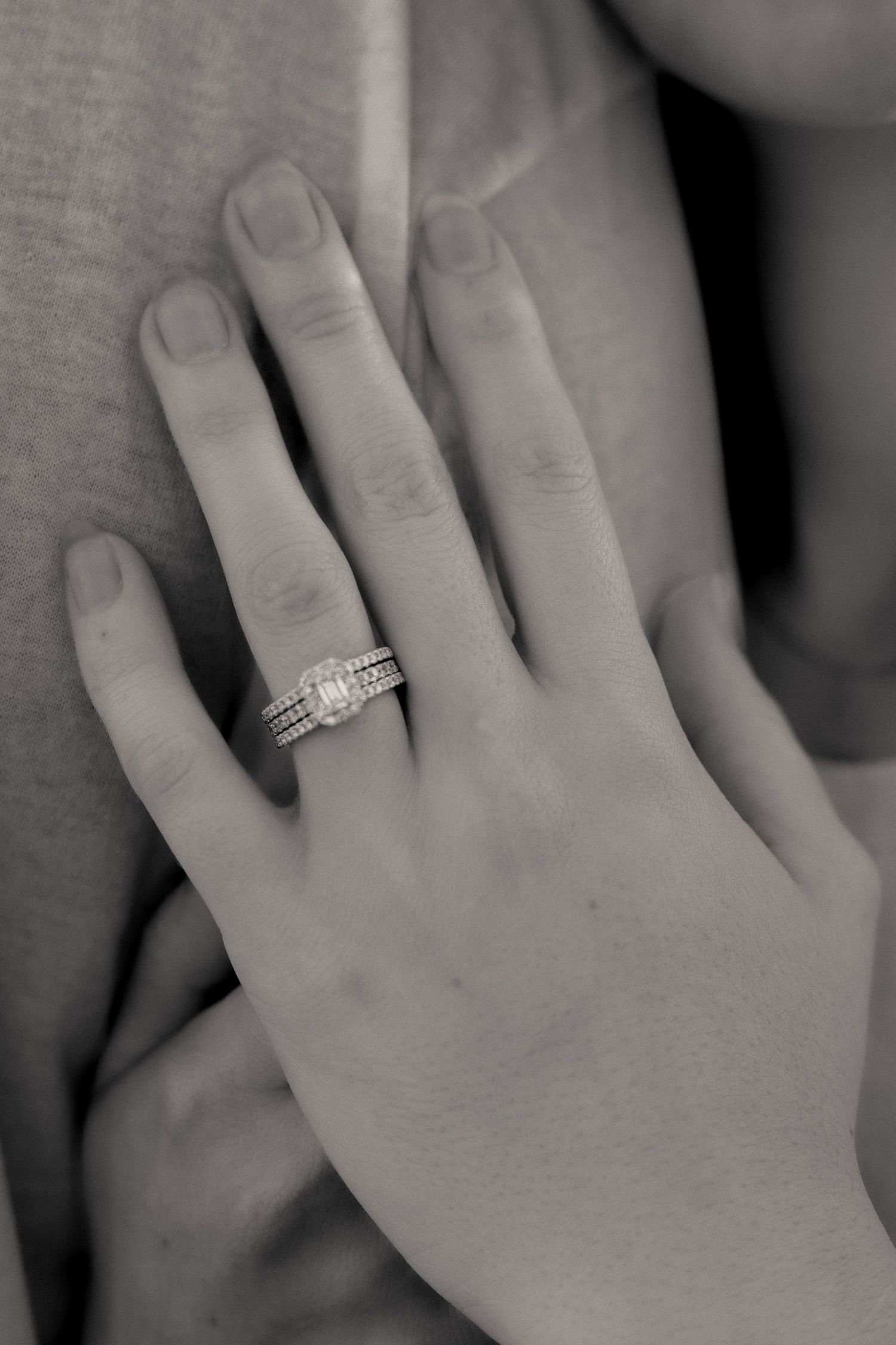 Close-up of engagement ring on woman's hand in black and white.