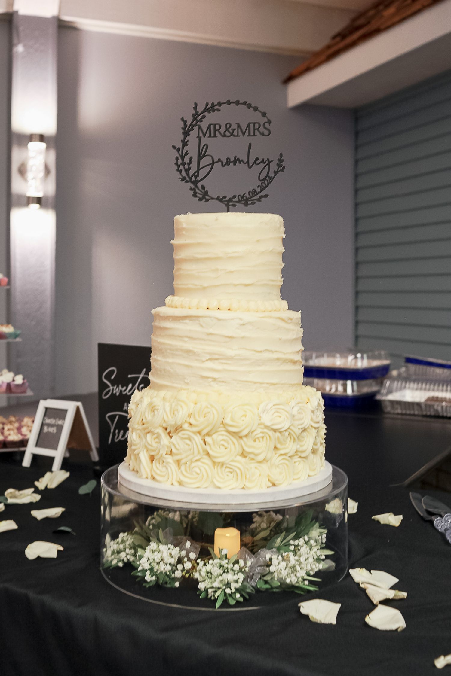 Elegant three-tier white wedding cake with textured buttercream frosting, rose details, and a Mr & Mrs topper.