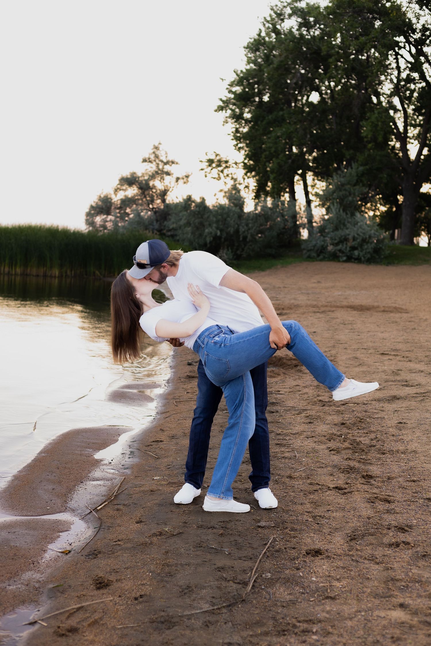 A playful dip pose of a couple on a beach at sunset.