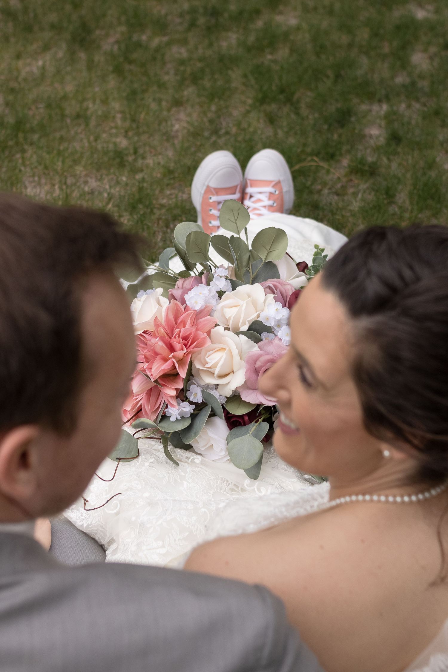 A creative overhead wedding photo showing pink floral bouquet and casual sneakers.