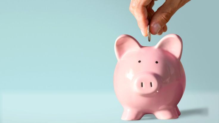 A line of pink ceramic piggy banks sit on a white surface against a blue background, showing progression in size.