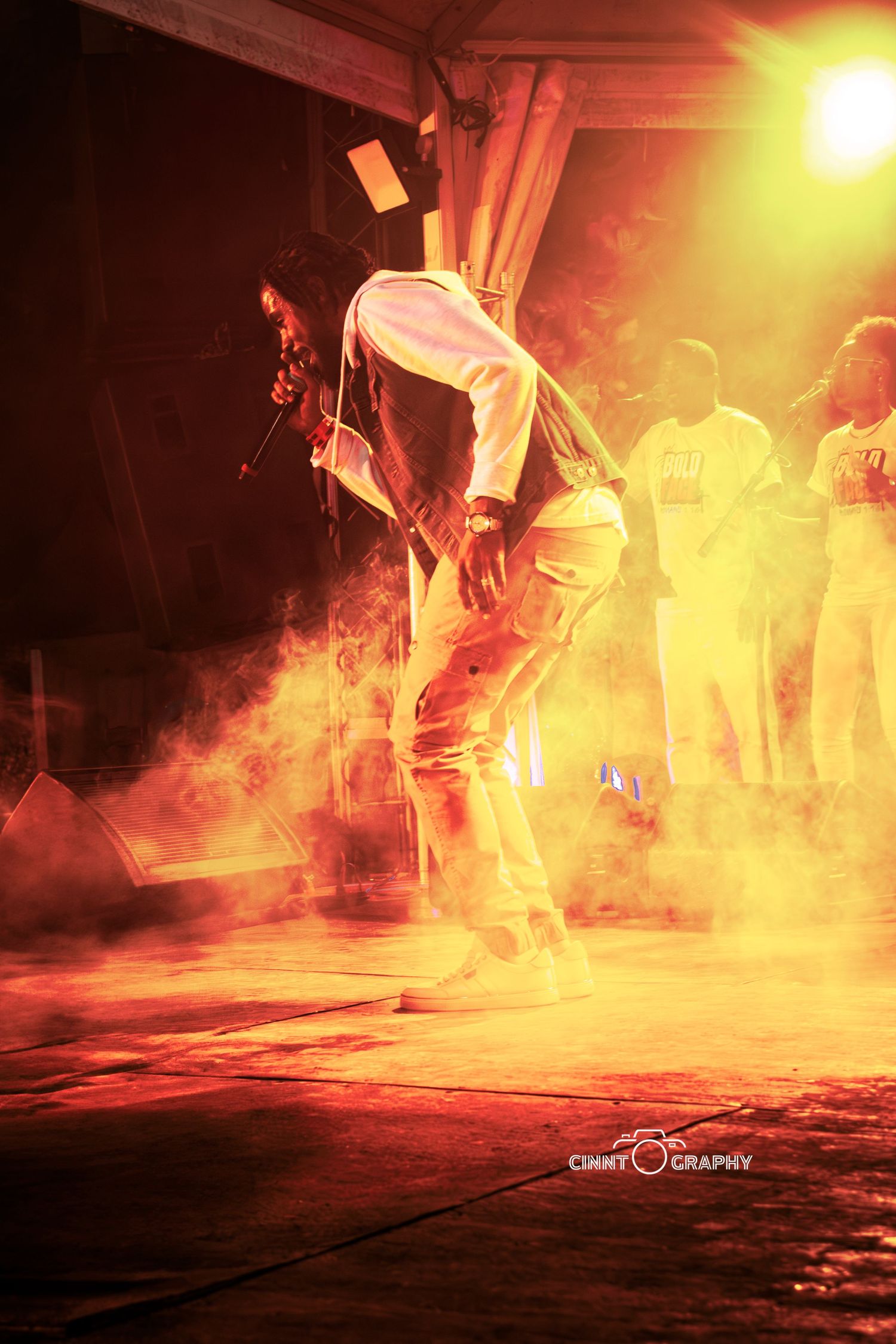 Dancer performs dramatic breakdancing move in orange-lit smoky performance space creating dynamic silhouette effect.