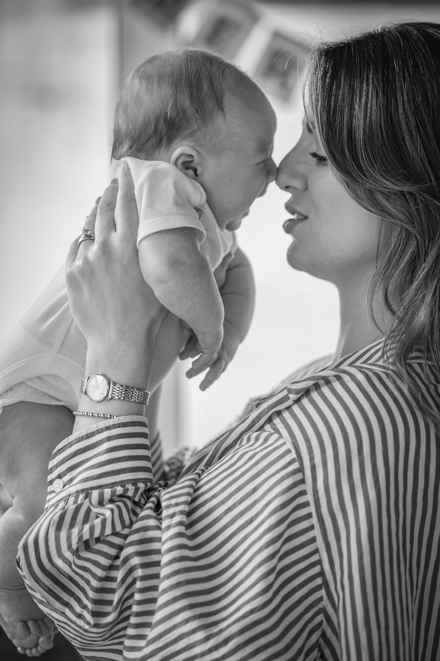 Black and white photo series showing tender moments between parent and baby in matching striped shirts.