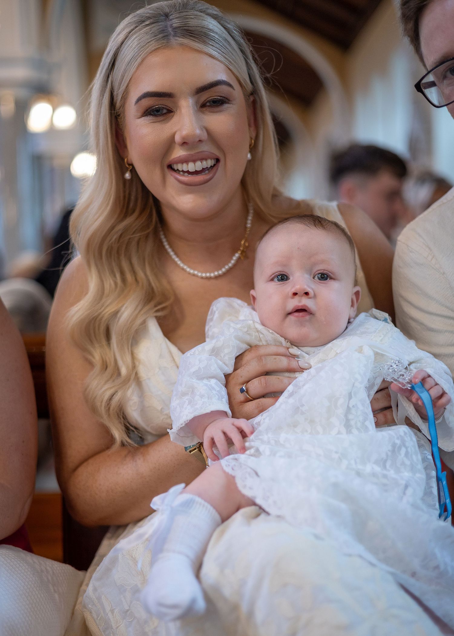 Baby in white christening gown being held during special ceremony with multiple candid moments.