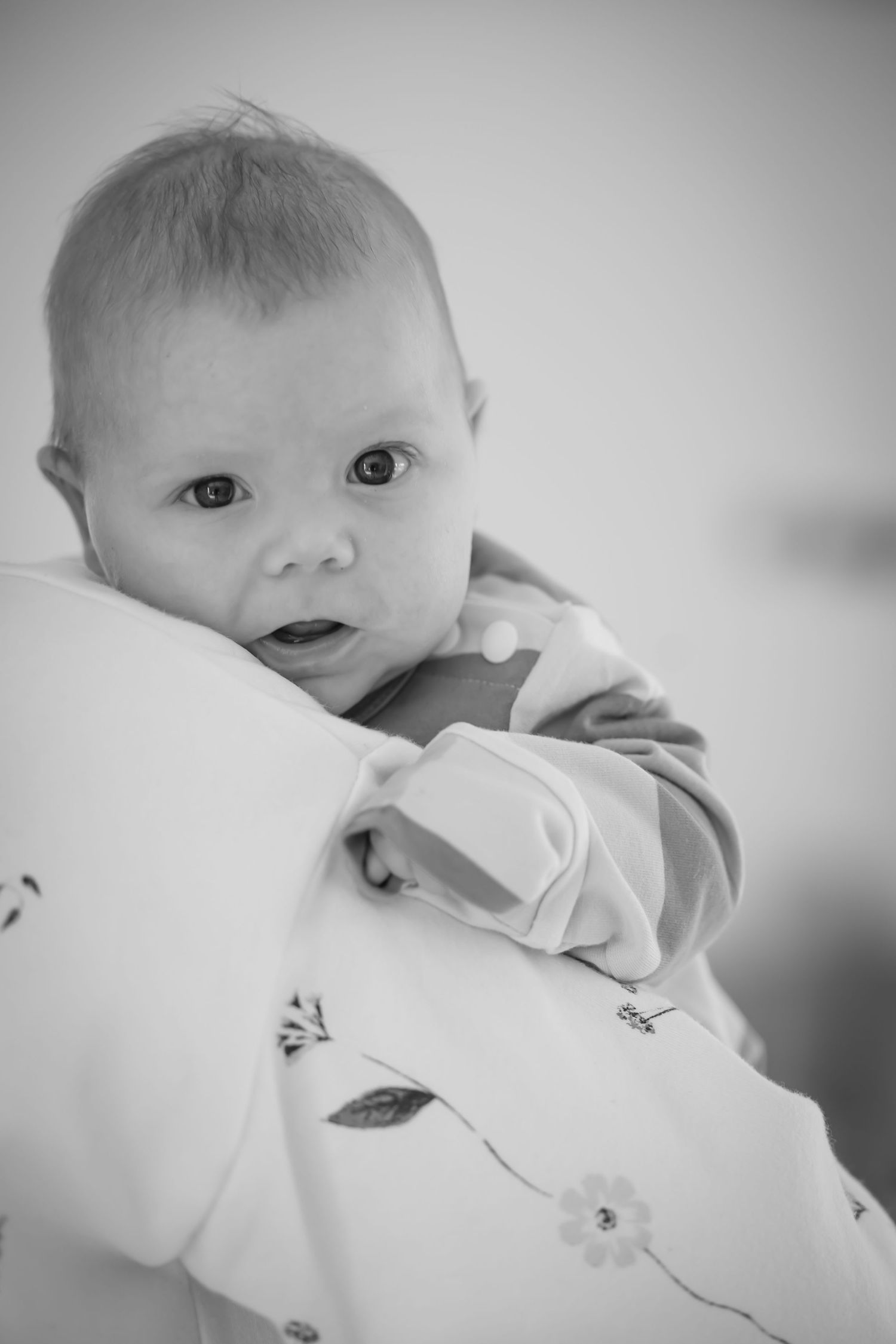 A black and white photo series showing a baby in white clothing making various facial expressions.