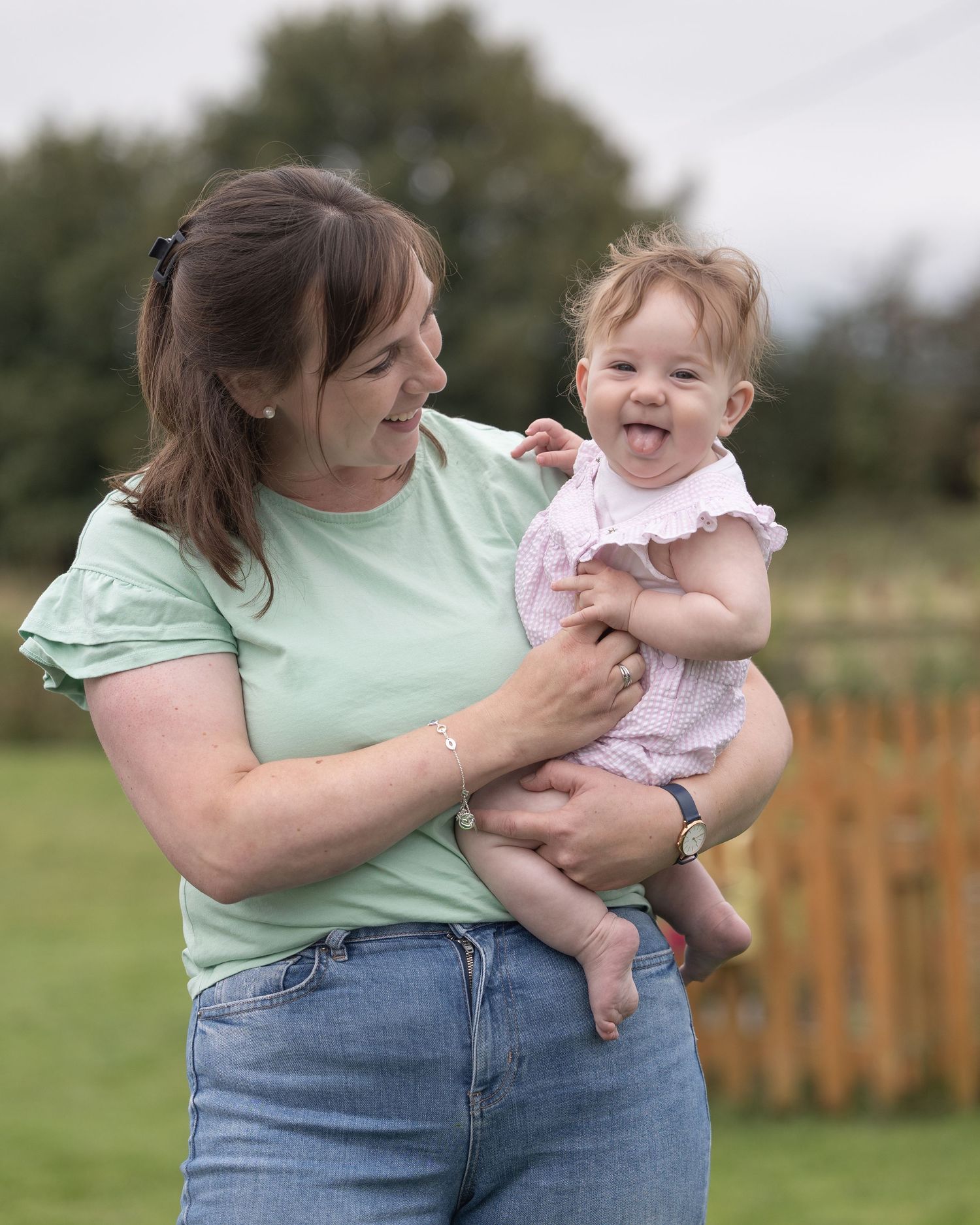 A parent in mint green shirt and jeans holds and plays with a baby outdoors in a sequence of candid moments.