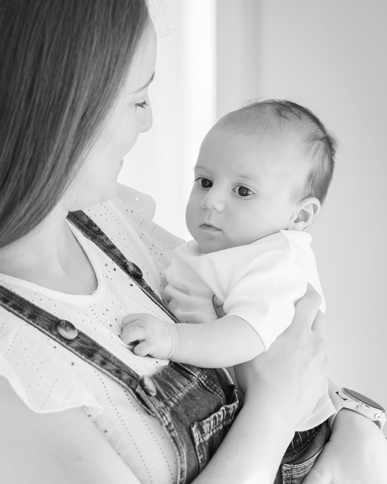 A tender black and white series showing a parent and baby in intimate bonding moments against a light background.