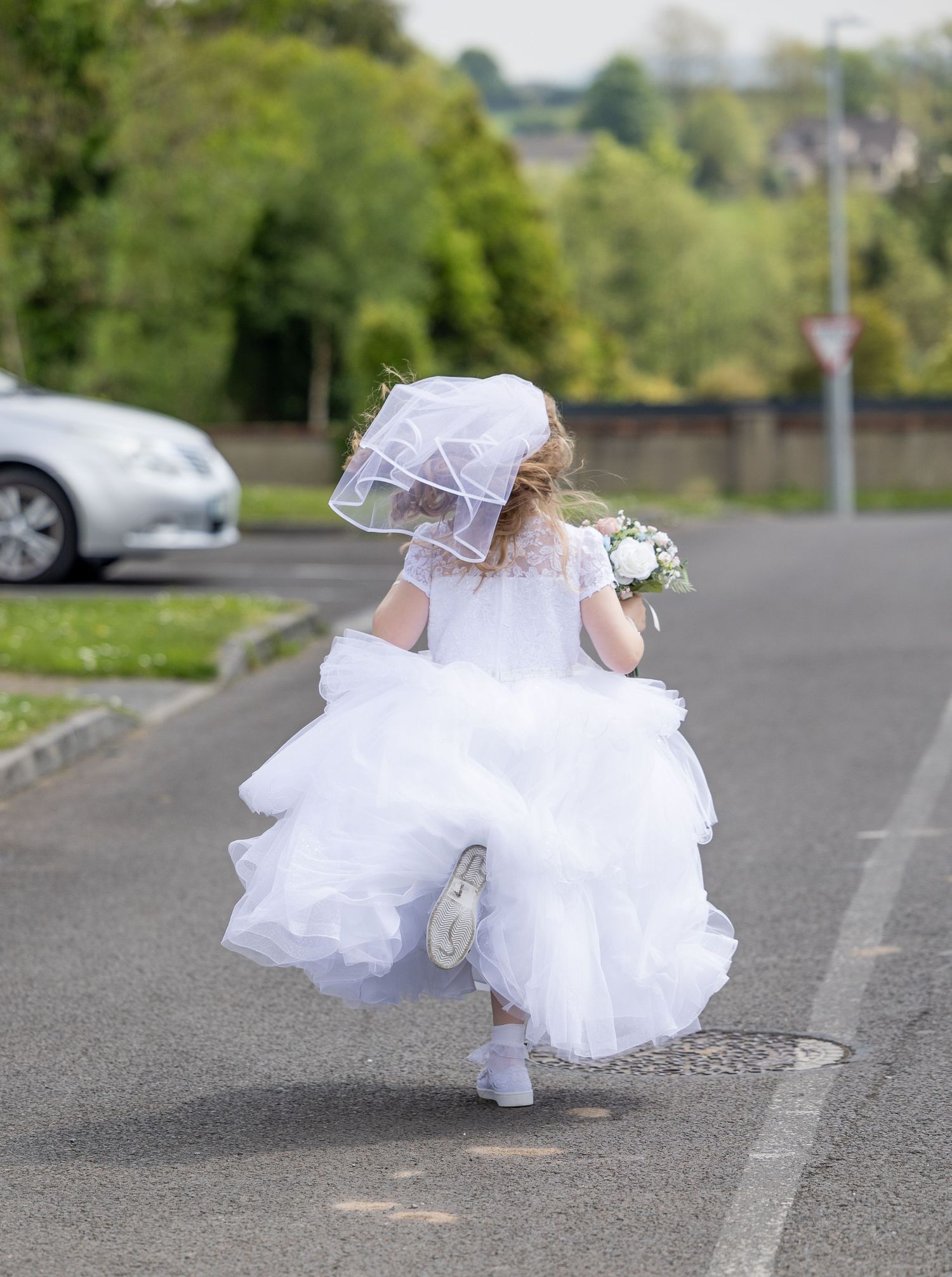 A sequence of photos shows a bride in a flowing white dress twirling and dancing on an empty road surrounded by greenery.