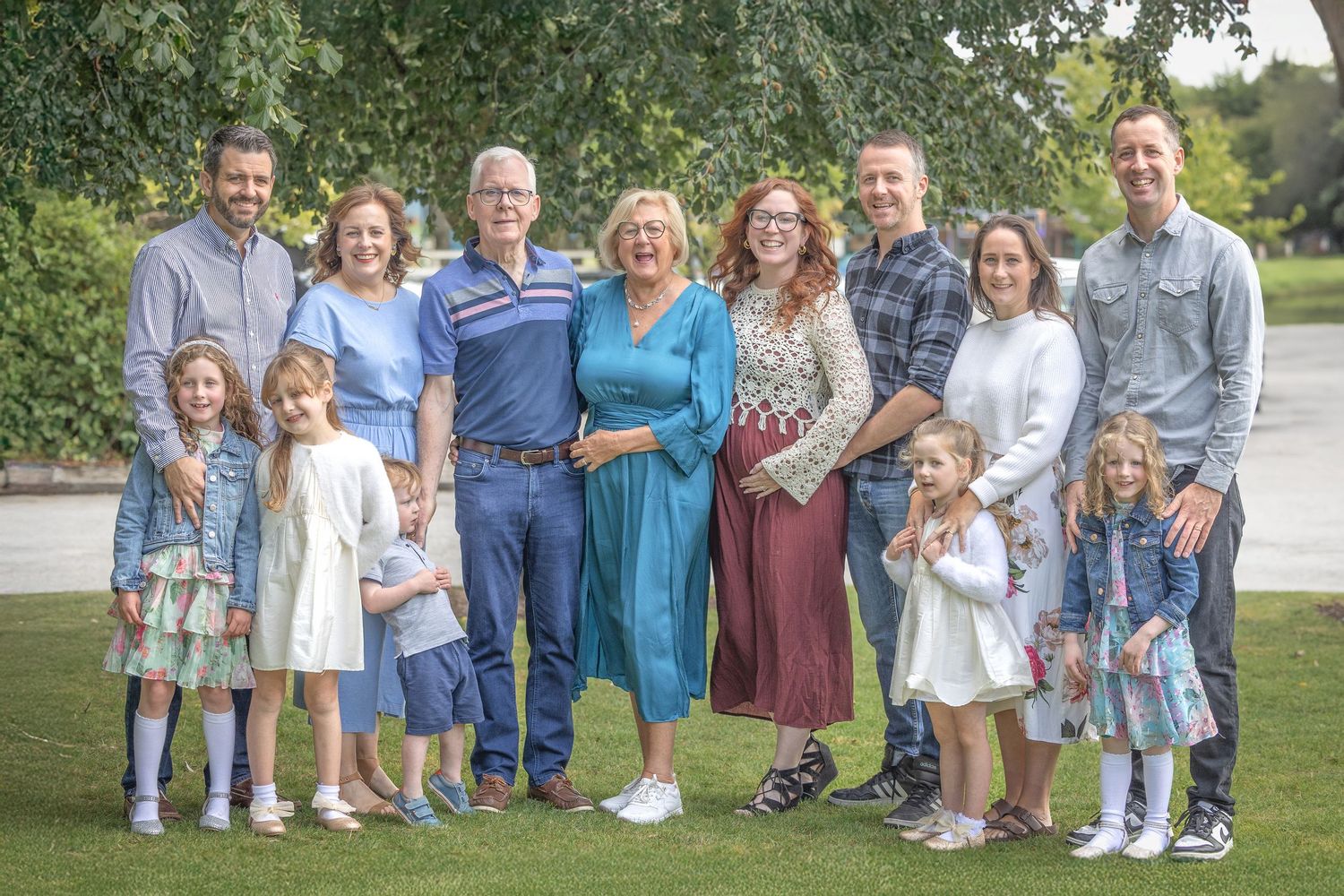 Large family group photo session outdoors with multiple generations posed together.