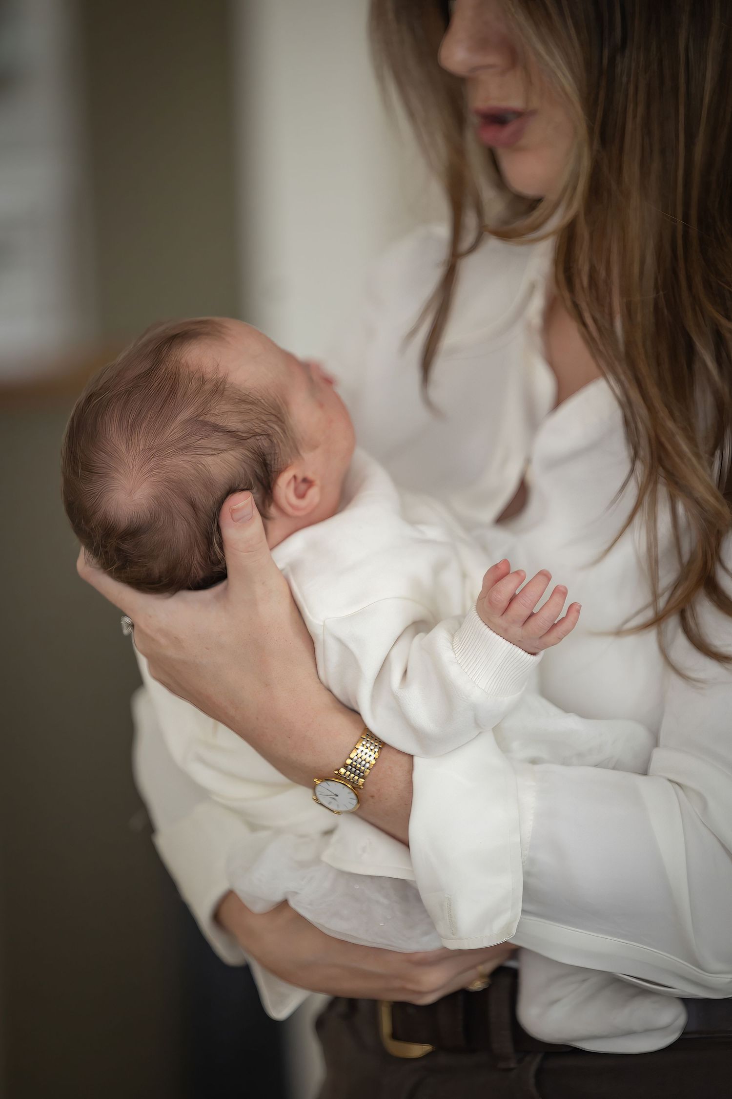 A series of tender moments showing someone in white holding and cradling a newborn baby.