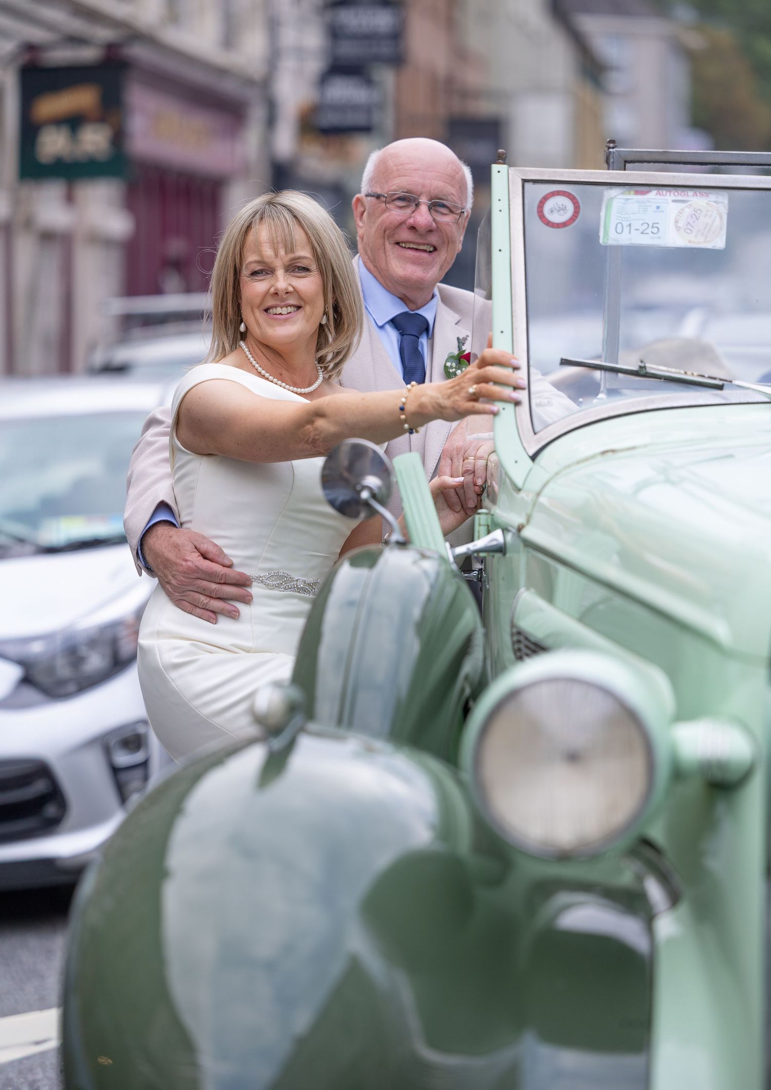 Couple posing with a vintage mint green scooter on a city street.