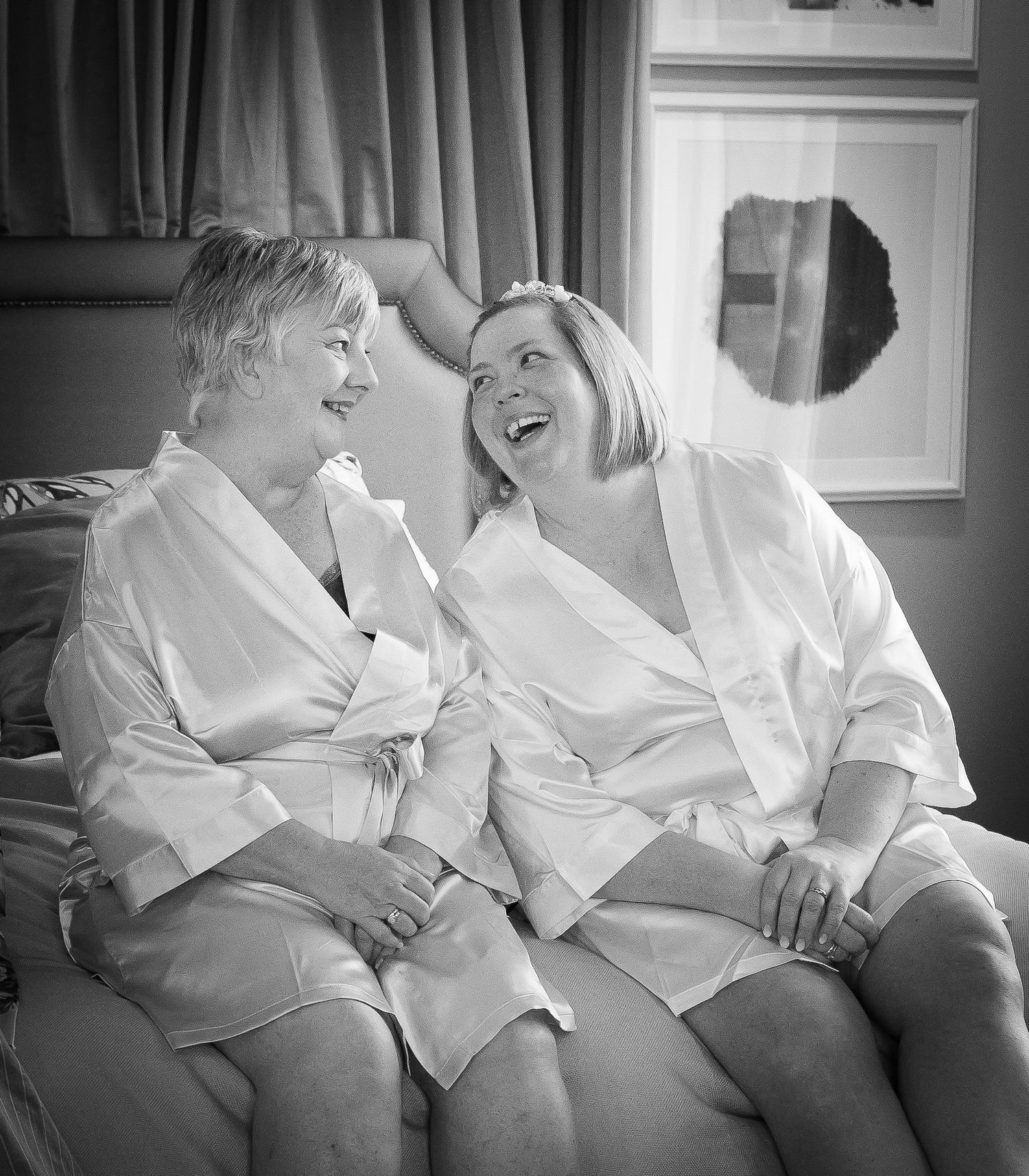 Black and white photo series showing intimate moments between two people in white shirts sitting together on a couch.