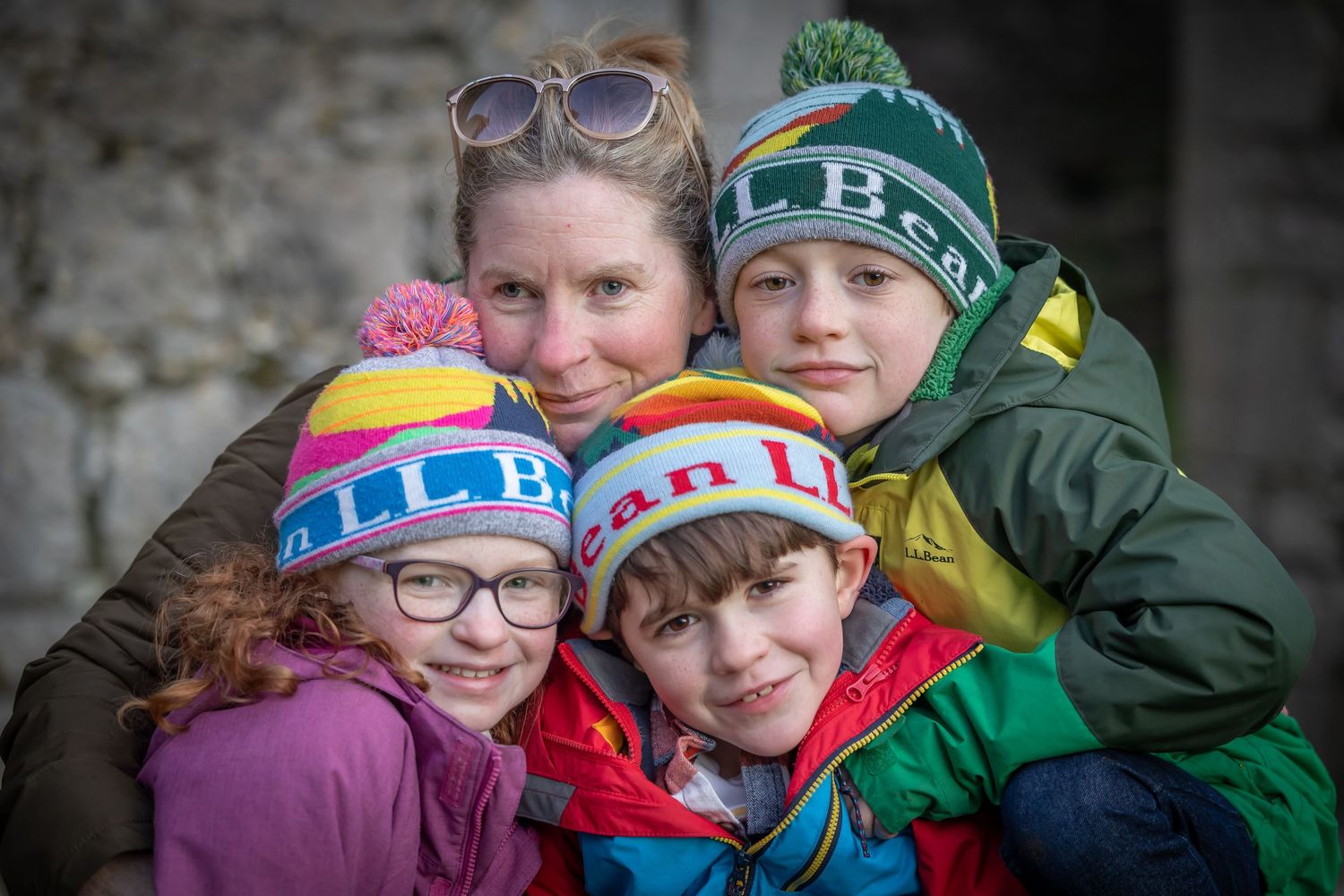 Group of friends wearing colorful winter hats and coats huddle together for a cheerful outdoor photo.