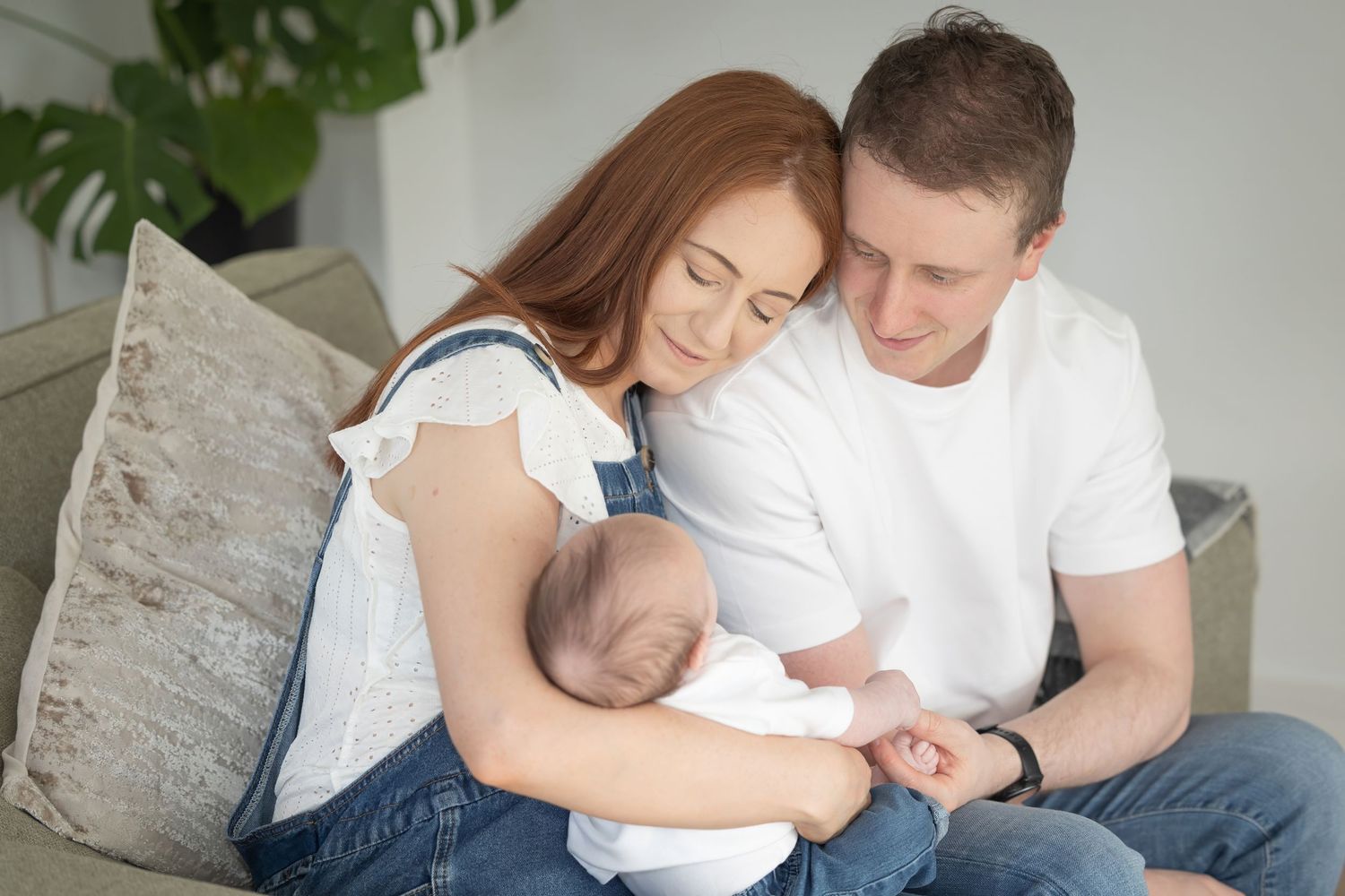 A series of intimate family moments showing parents and newborn baby relaxing together on a white couch.