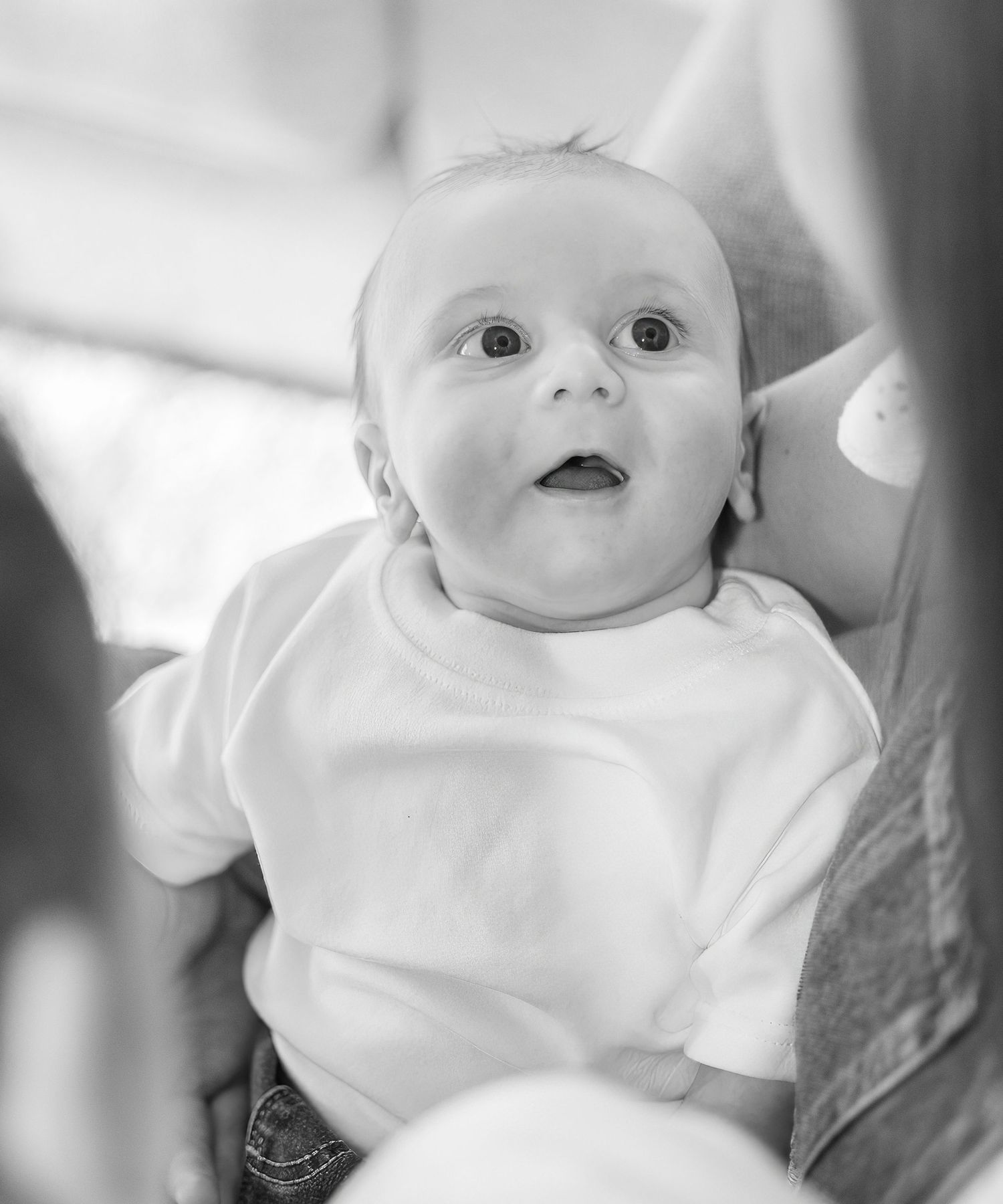 Black and white portrait series of a baby in white clothing showing various expressions and poses.