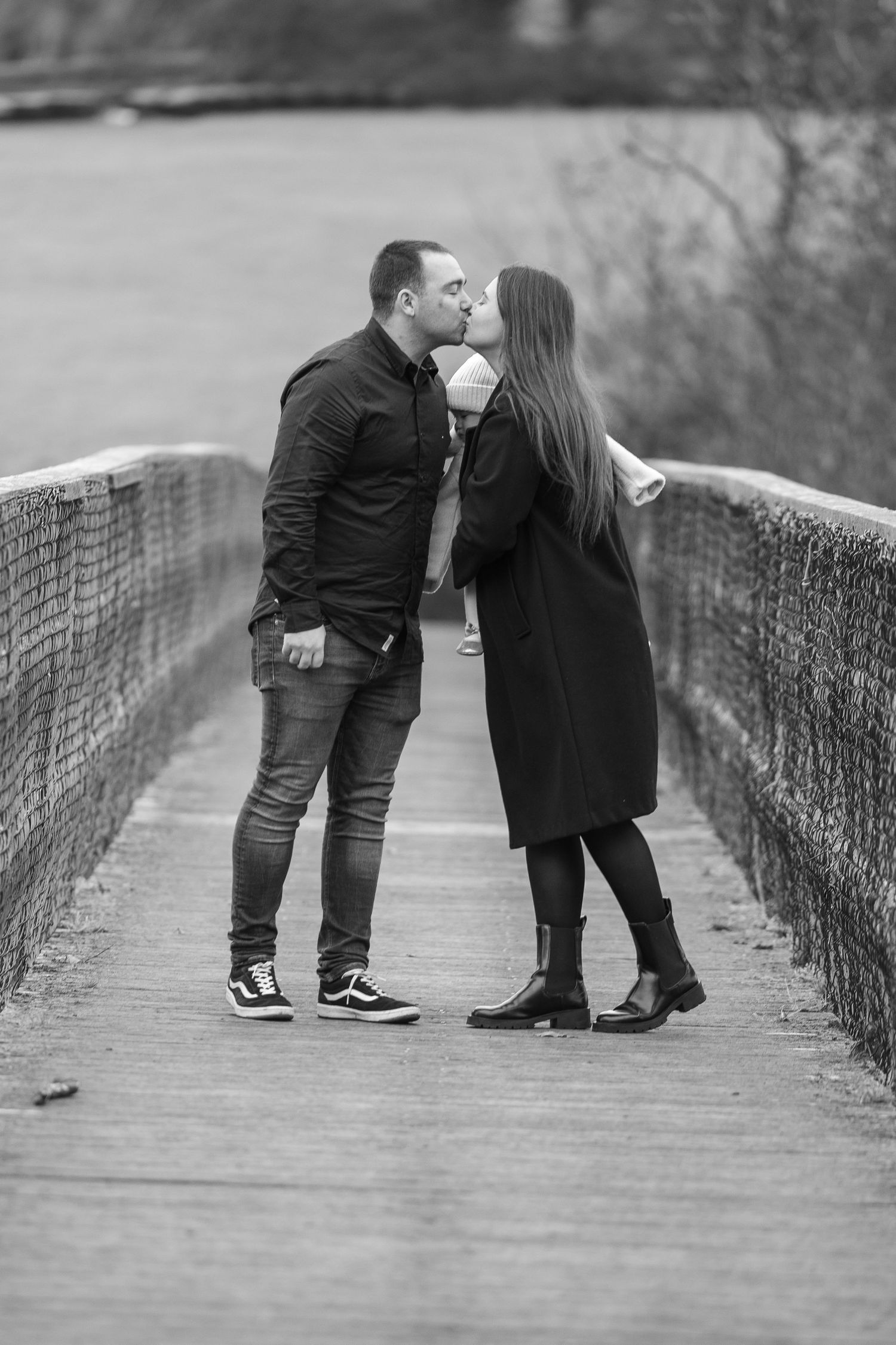 A romantic black and white sequence shows a couple sharing a kiss on a wooden bridge walkway.
