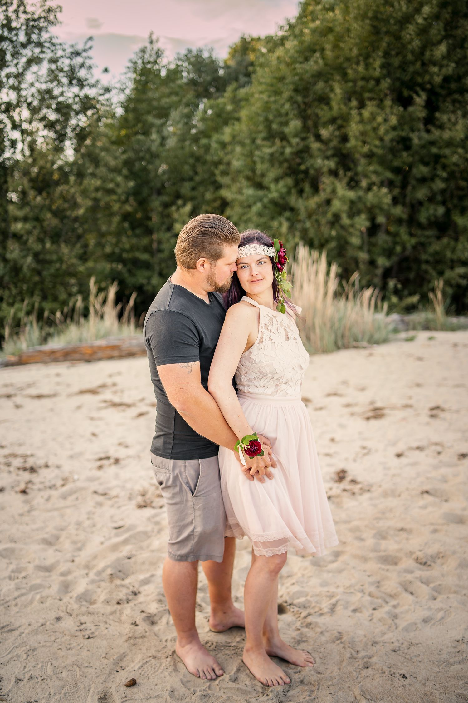 A romantic beach photoshoot scene on sandy shores with trees in the background at sunset.