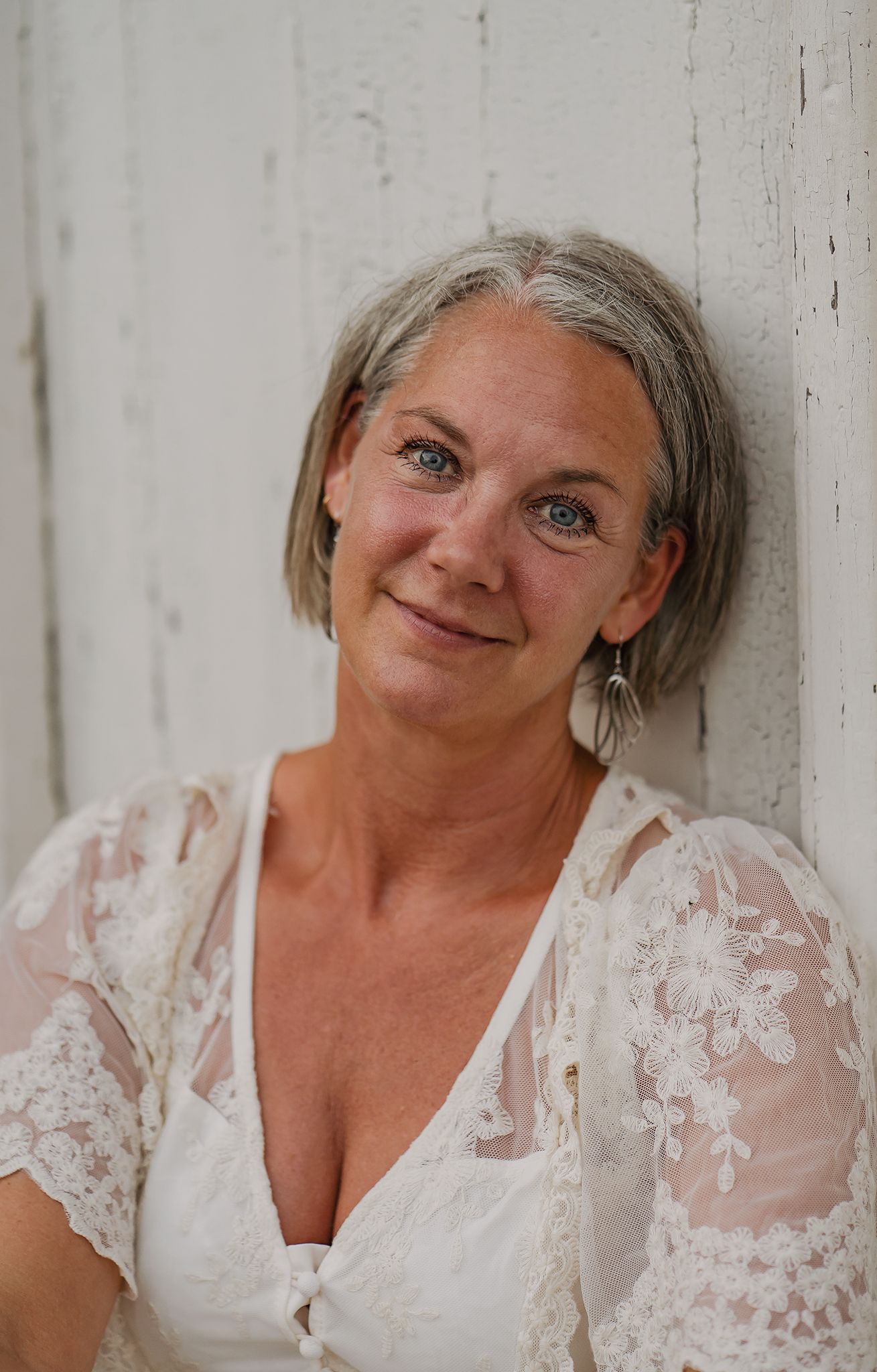 Portrait against white wall showing person in delicate lace dress with natural lighting.