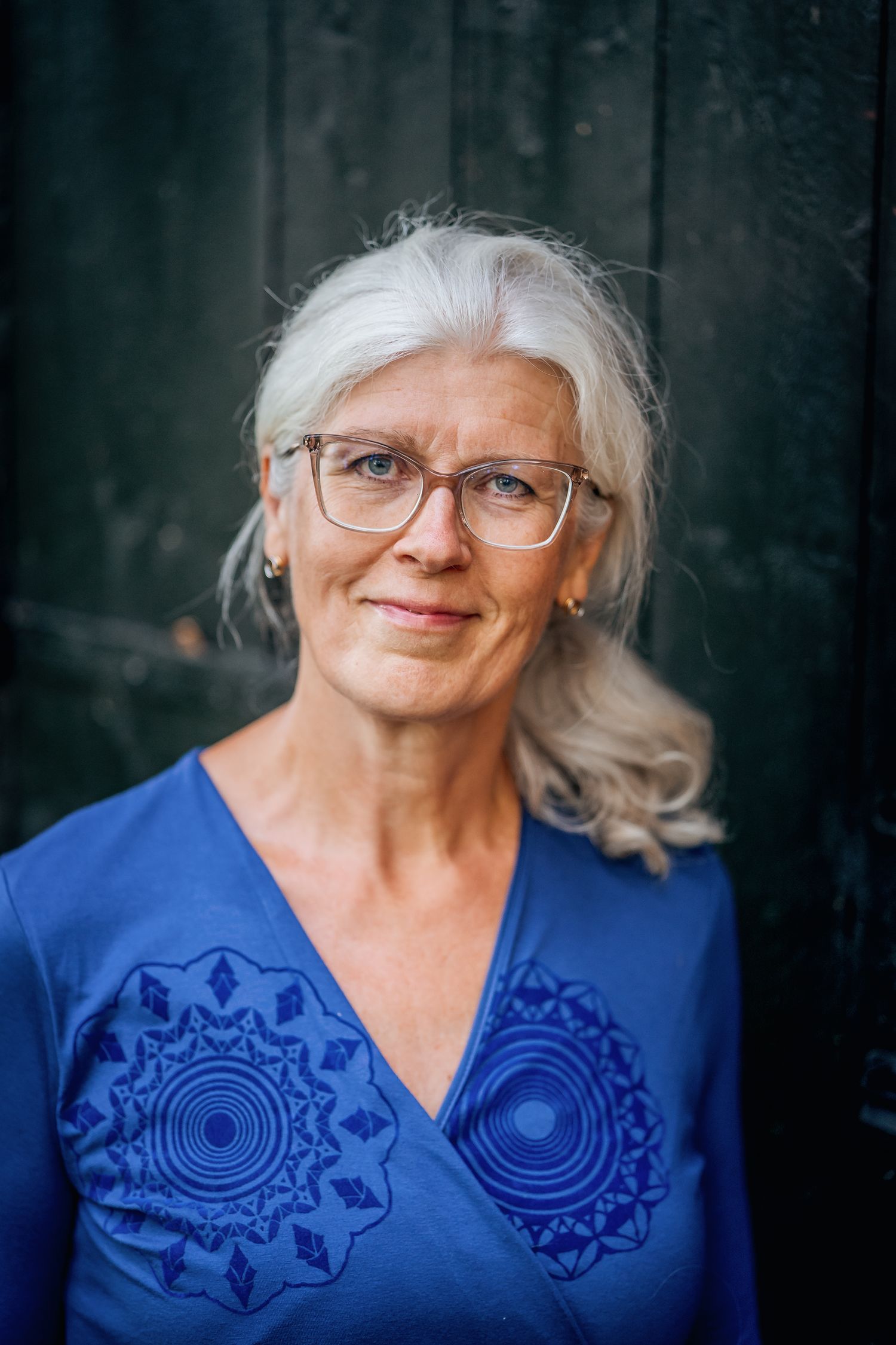 Portrait of someone wearing glasses and a vibrant blue embroidered top in a series of candid expressions.