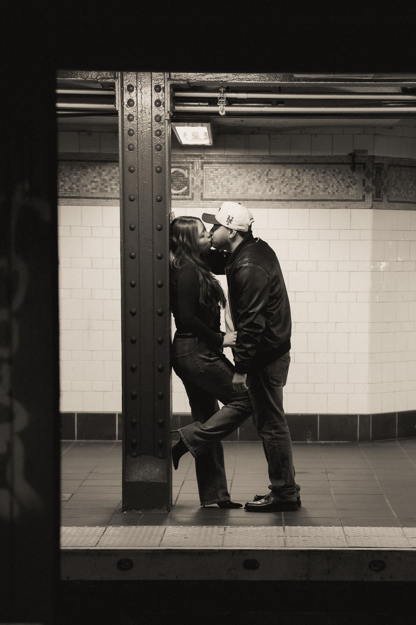 A sepia-toned photograph captures an intimate moment in a subway station.