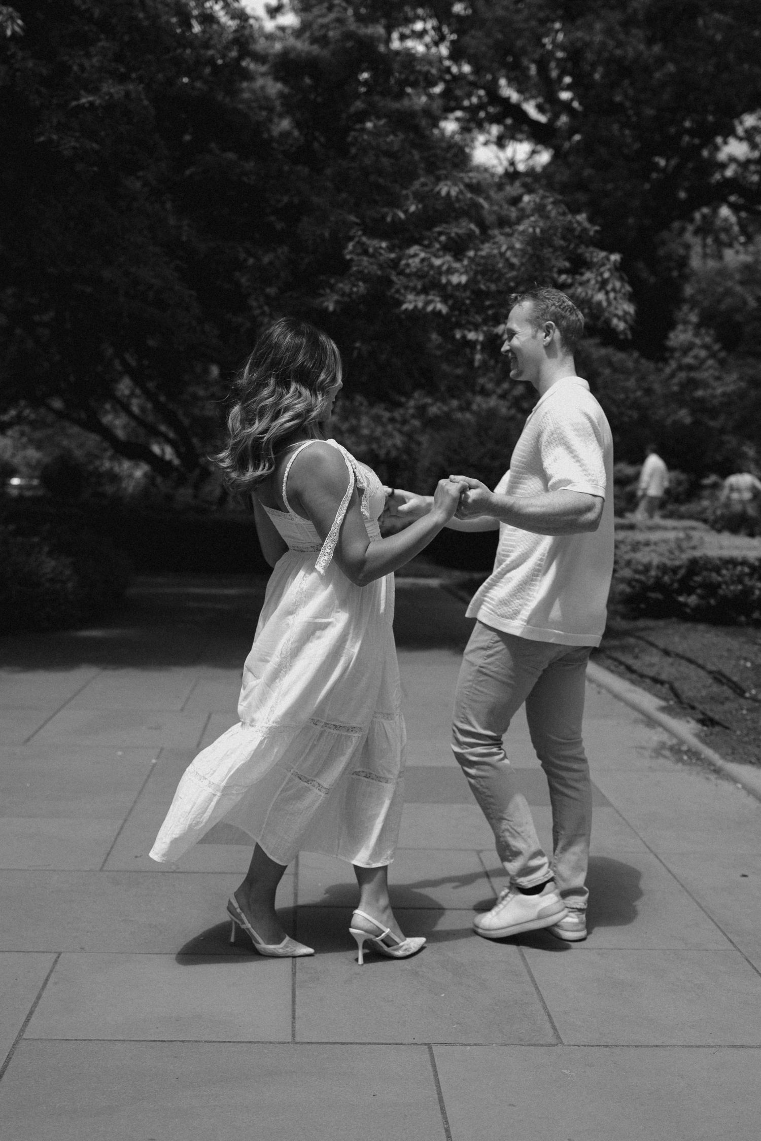 Black and white sequence showing playful dance movements on a stone pathway.