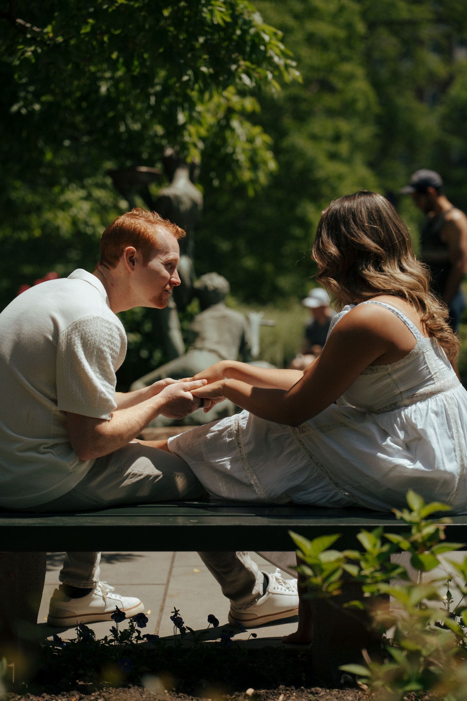 A couple shares intimate moments while lounging on a blanket in dappled sunlight.