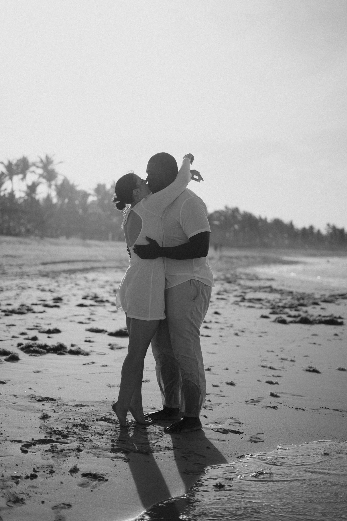 Couple embracing and kissing on a tropical beach in black and white romantic photo.