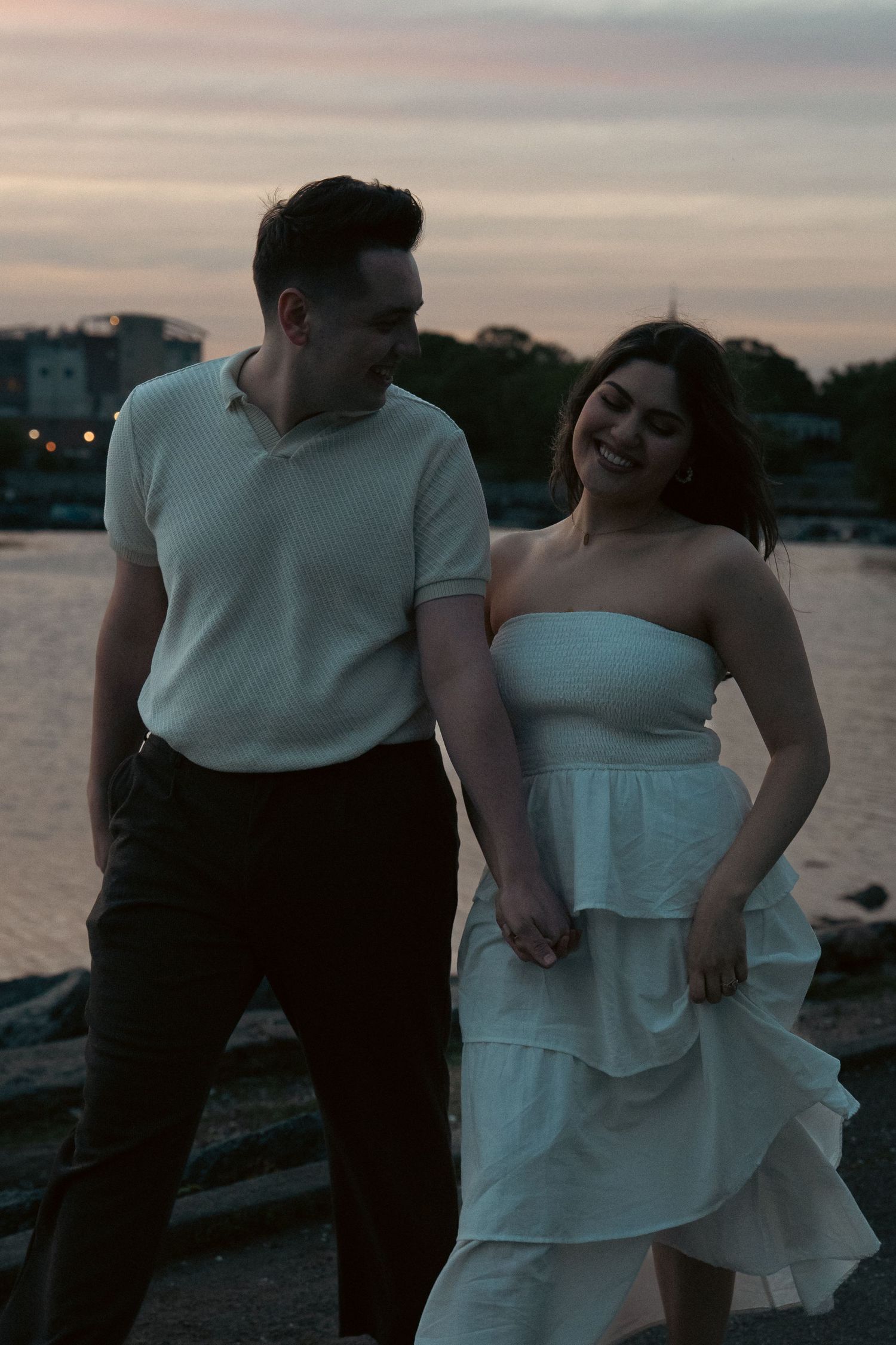 A couple sharing playful moments together at sunset by the waterfront.